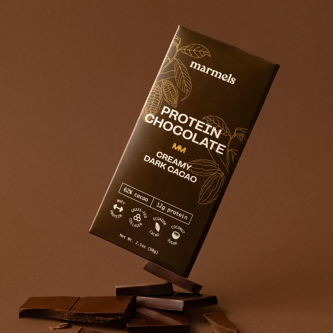 Creamy Dark Cacao protein chocolate bar standing on pieces of dark chocolate 